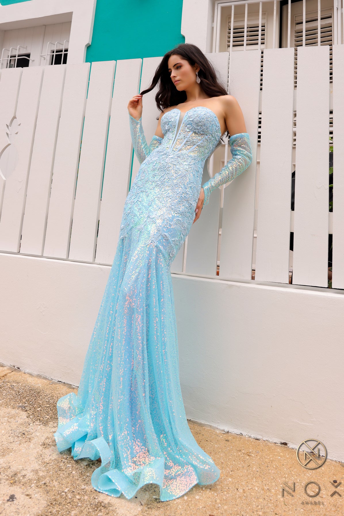 Expertly crafted with a flattering mermaid silhouette and intricate lace corset, the Nox Anabel D1263 Prom Dress will turn heads at any formal event. Featuring long sleeves and a stunning sequin design, this dress offers a unique and elegant option for your next special occasion.  Sizes: 00-16  Colors: Baby Pink, Black, Light Blue