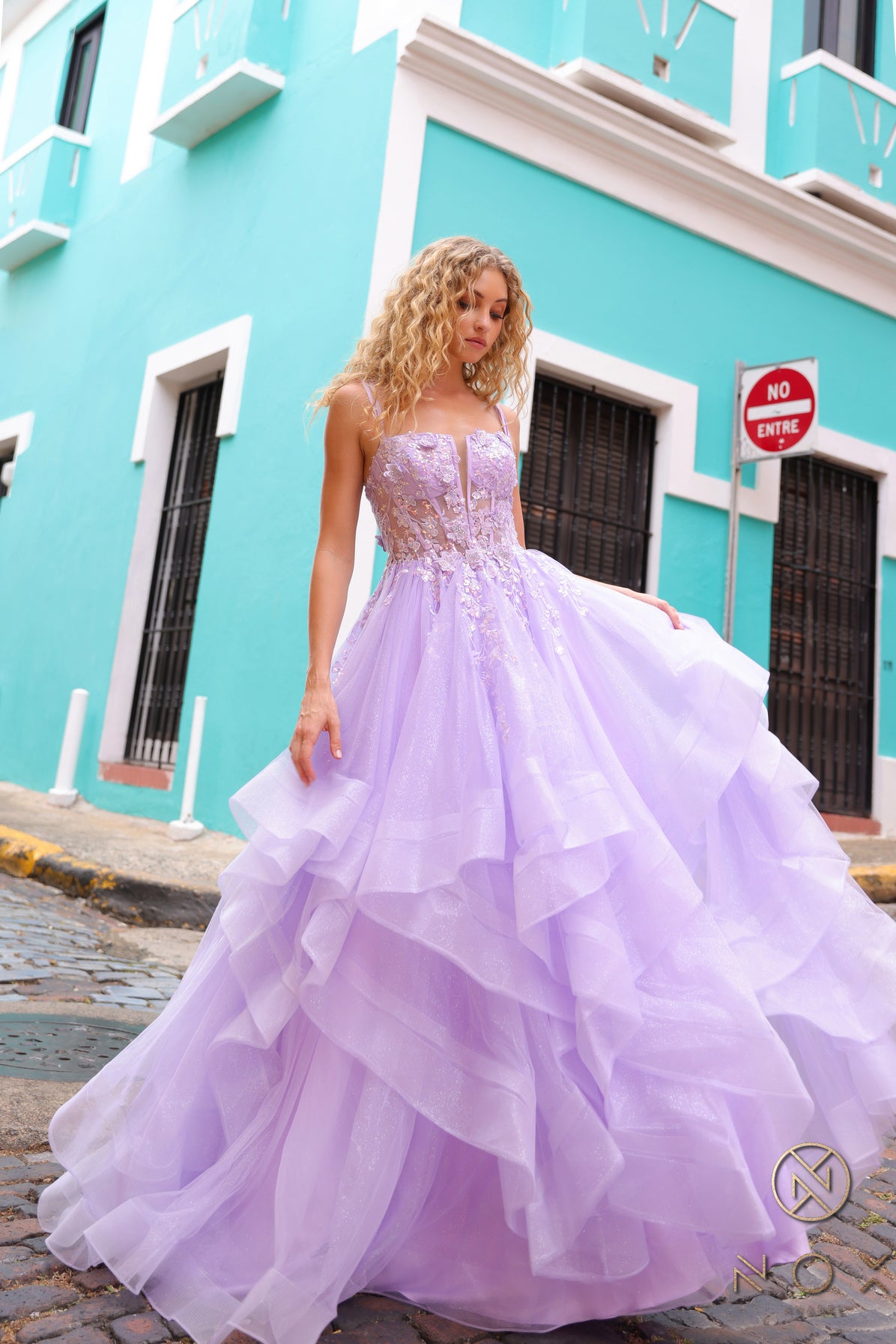 This Nox Anabel H1351 Prom Dress is the perfect combination of elegance and flair. Designed with a shimmering ruffle ballgown and a sheer sequin corset, this dress will make you stand out at any formal event. The v neck adds a touch of sophistication, making you feel like royalty.  Sizes: 0-16  Colors: Hot Pink, Lilac, Orange, Periwinkle, Royal Blue