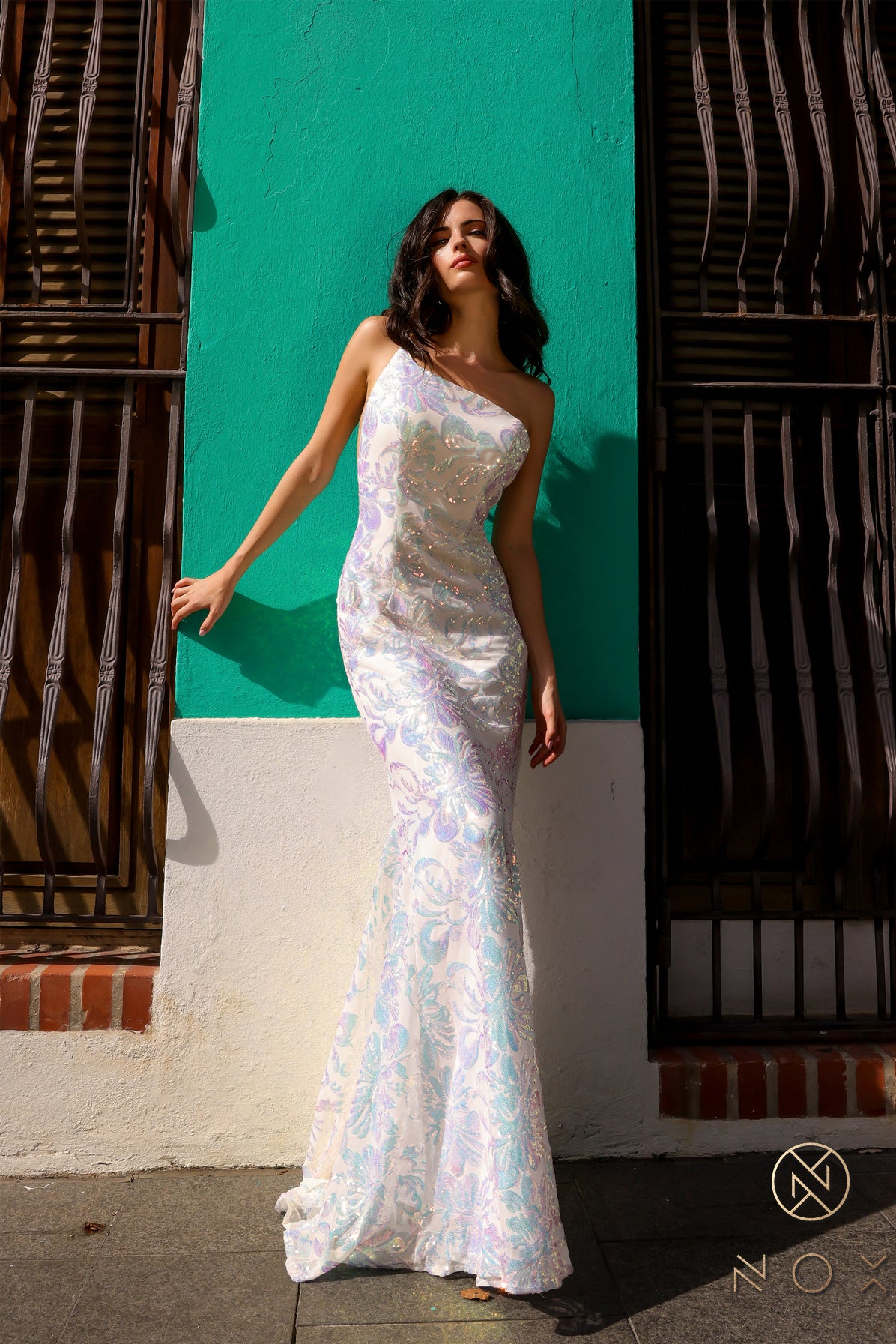 Be the ultimate showstopper in this stunning Nox Anabel R1308 sequin lace one shoulder prom dress. The mermaid silhouette and formal design will give you the confidence to shine on any pageant stage. Guaranteed to make a lasting impression, this gown is a must-have for any special occasion.  Size: 0-16  Colors: Fuchsia, Aqua Blue, White Multi