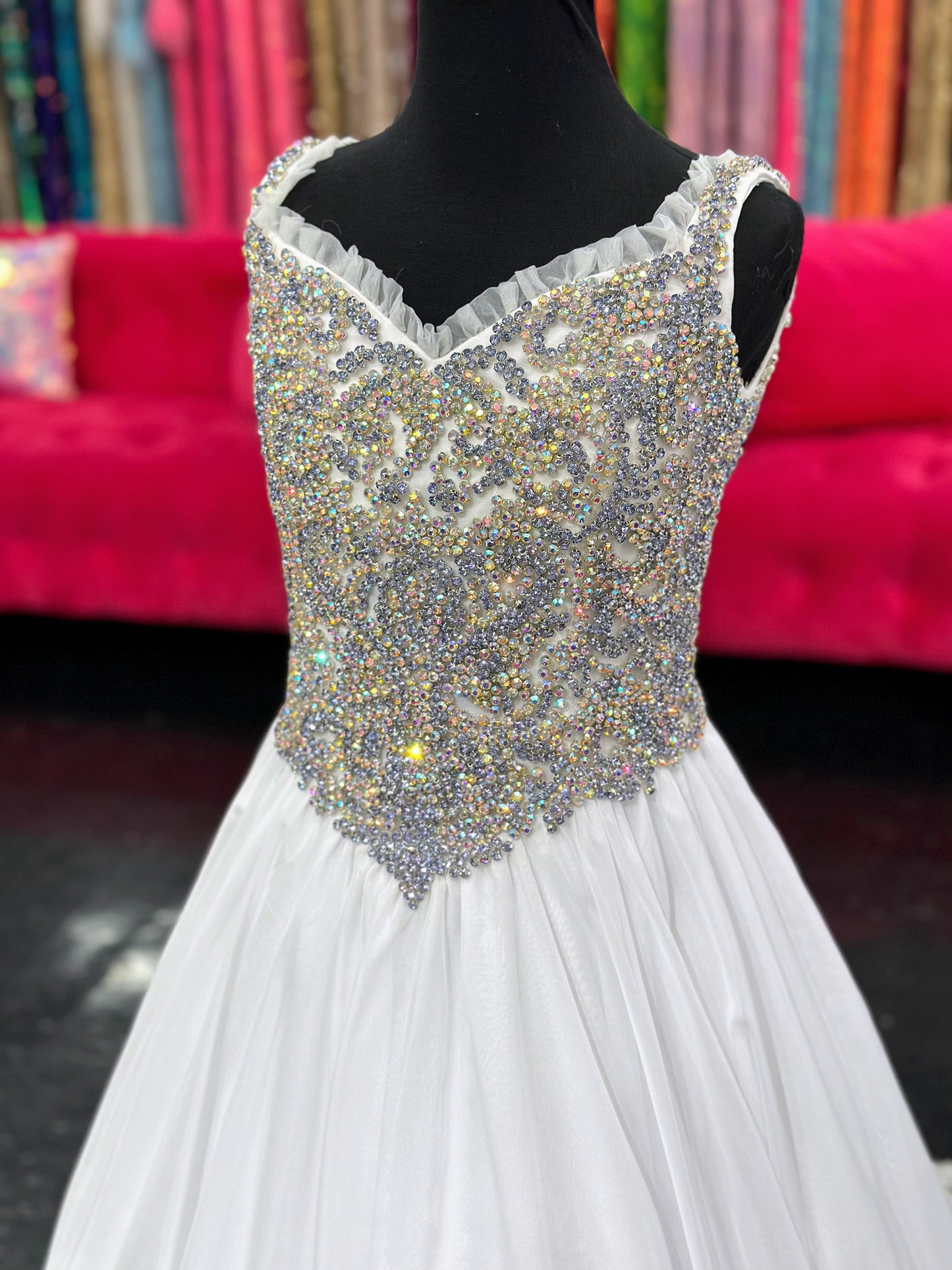 Experience the luxurious elegance of the Samantha Blake 1127 Pageant Dress. Made with soft, lightweight chiffon, this A-line ballgown will have your little girl feeling like a true princess. The crystal embellished bodice and ruffle trim neckline add a touch of sparkle and charm. Perfect for any pageant or special occasion.