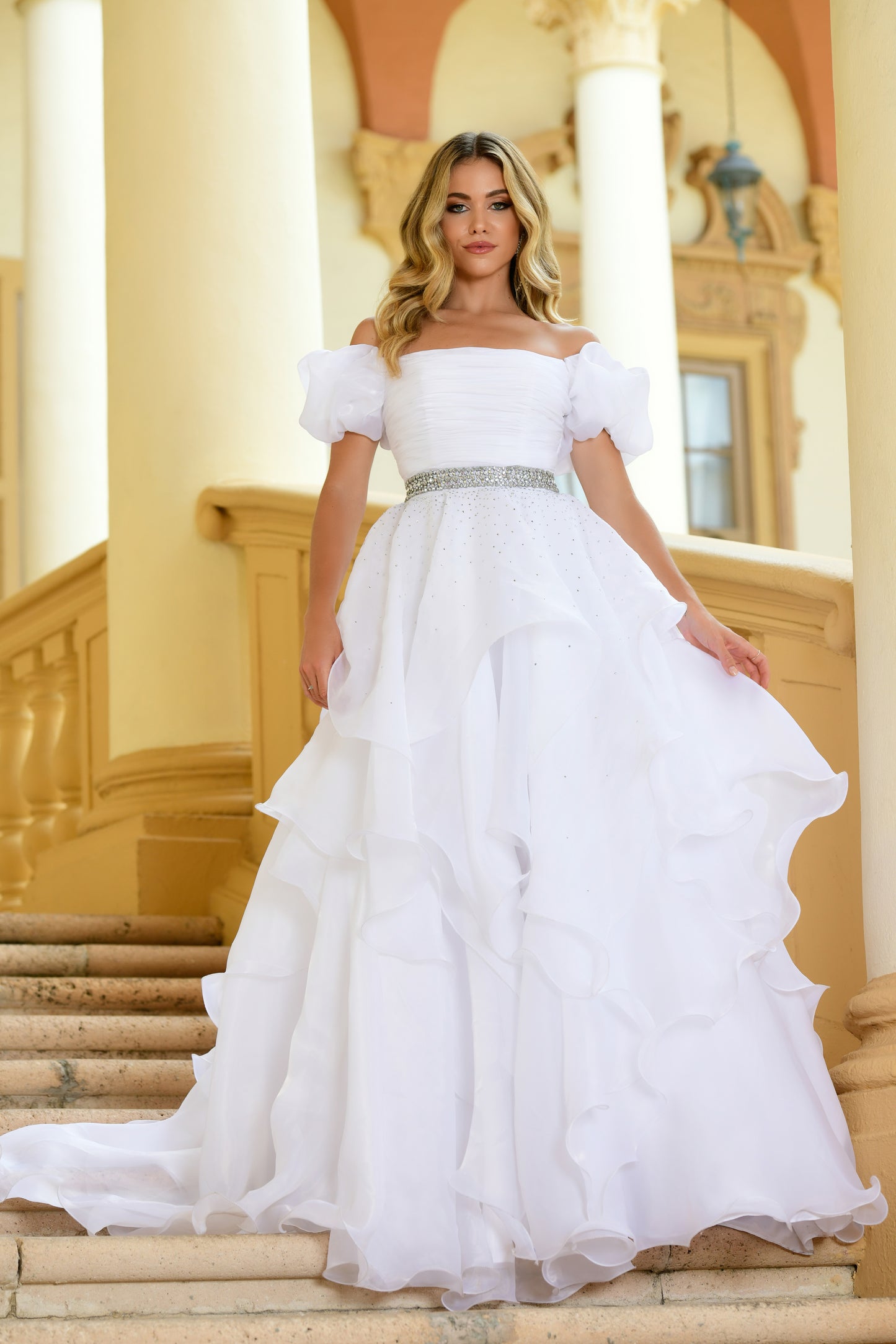 Introducing the Ava Presley 28571 Dress, perfect for any pageant or special occasion. It features a long ruffle ballgown style along with an off-the-shoulder, puff sleeve design. Crafted from a premium quality fabric, this gown is lightweight, durable, and provides a comfortable fit. Get ready to sparkle and shine in this gorgeous dress.  Sizes: 00-18  Colors: Black, Fuchsia, Light Blue, Red, Royal, White, Orchid