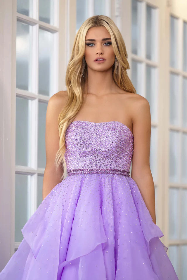 Add a touch of elegance to any formal event with the Ava Presley 39561 Long Prom Dress. The beaded bodice and halter top provide a dazzling look, while the crystal belt-line and layered ruffles add texture and movement. Perfect for prom, pageants, or any special occasion.