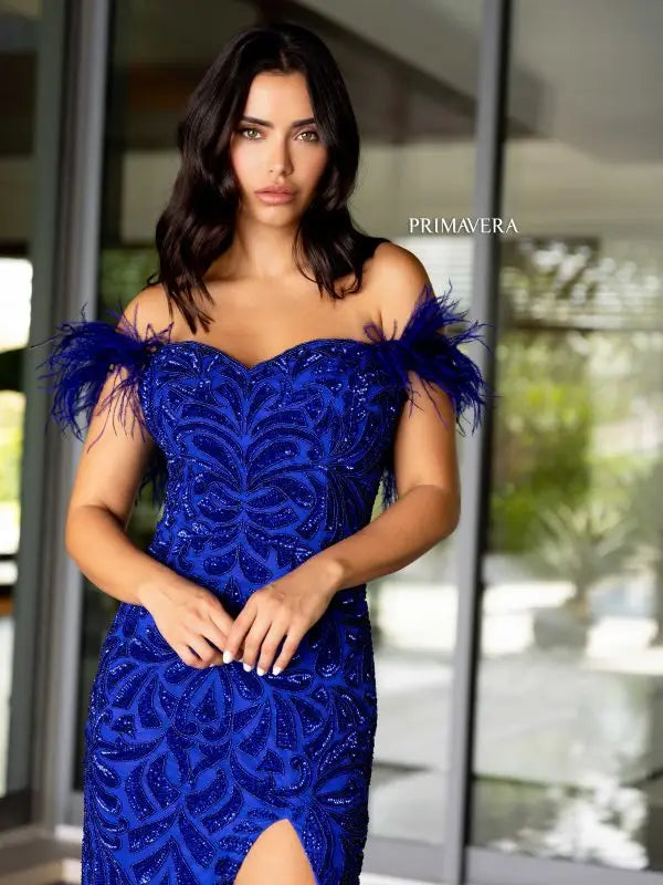 Elevate your style game with the Primavera Couture 4105 Long Prom Dress. Showcasing an off-shoulder design, this gown features a corset bodice adorned with feathers, sequins, and beads. Fitted and featuring a high slit, this formal pageant gown is perfect for making a statement at any event.