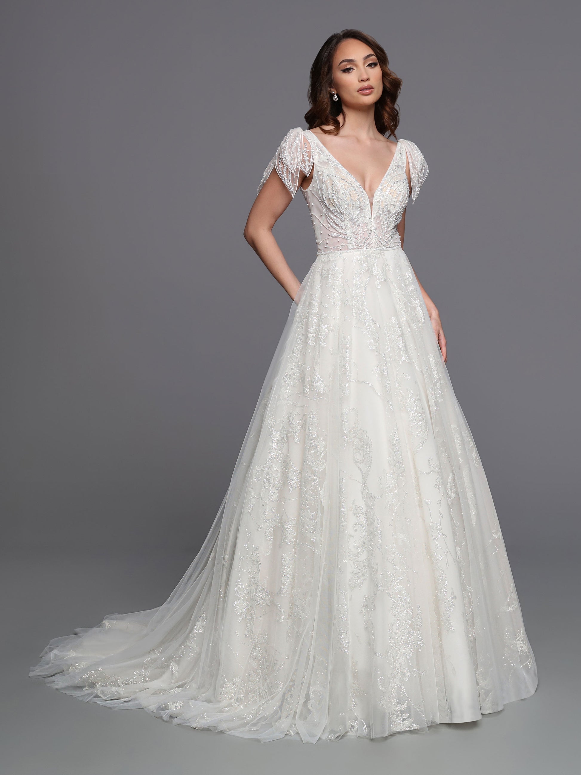 This Davinci Bridal 50718 Long Glitter Beaded Wedding Ballgown Dress is sure to make any bride sparkle. The A-line silhouette features embroidered patterned lace coupled with a beaded tulip-style cap sleeve, creating a sheer yet elegant fairytale look. The layers of tulle combine for an unforgettable wedding dress.  Sizes: 2-20  Colors: Ivory