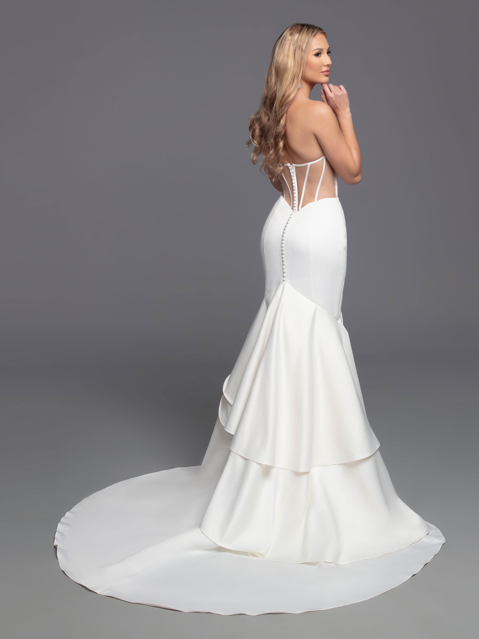 The Davinci Bridal 50808 Long fitted Strapless satin mermaid wedding dress boasts a beautiful modern design with a traditional flair. Its fit & flare silhouette is enhanced by an opaque ruched front bodice and a romantic ruffled mermaid skirt with a sheer back bodice. This stylish design is finished with covered buttons and a tiered back skirt, culminating in a chapel train.  Sizes: 2-20  Colors: Ivory, White