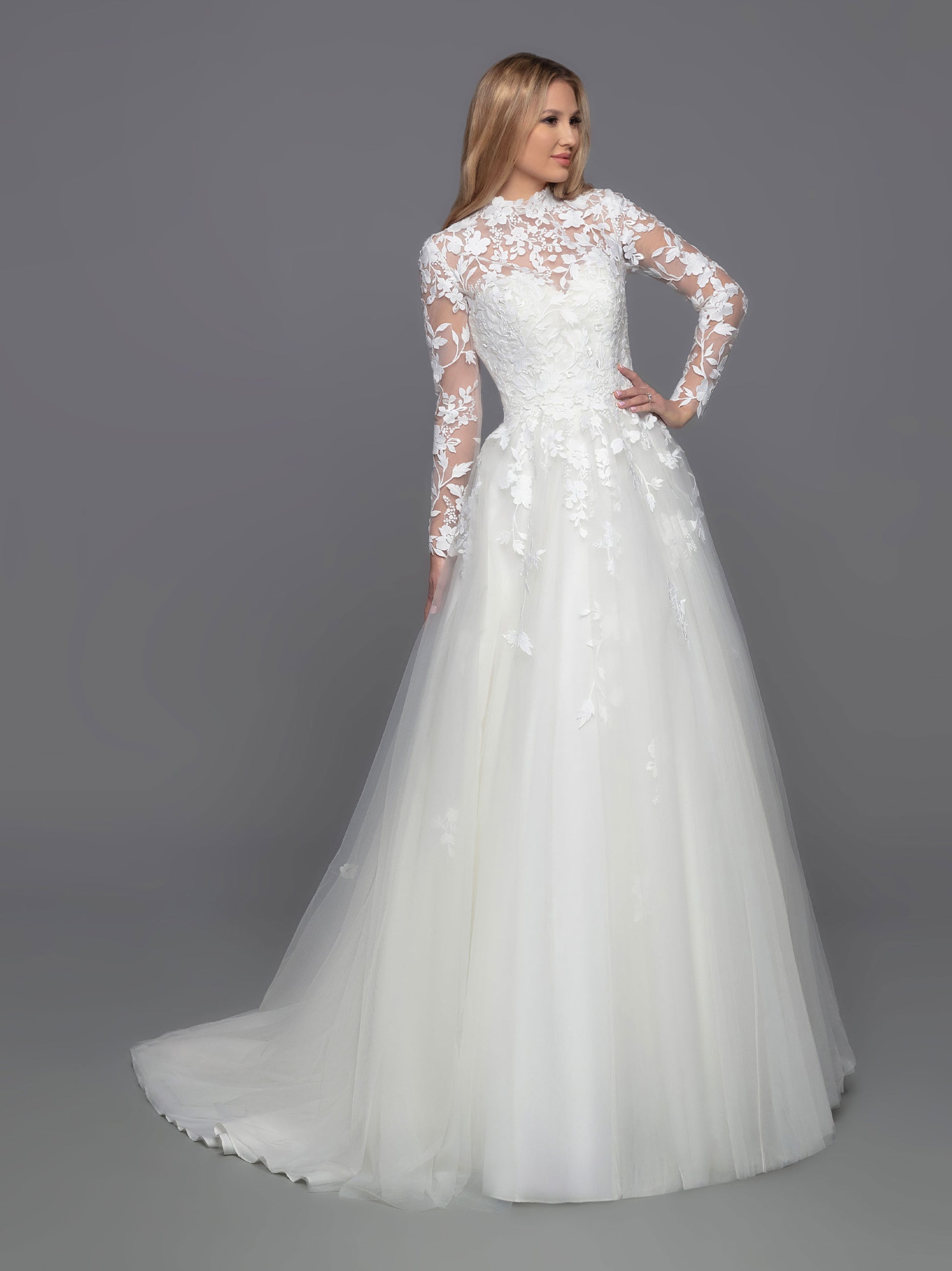 Look stunning on your big day with Davinci Bridal 50813. This beautiful tulle ballgown features a long a-line silhouette with a detachable lace long sleeve high neck jacket. Perfect for modest brides and cold weather weddings, the sheer lace bodice, back, and full-length sleeves create a breathtaking look. Lace accent at the waist of the layered skirt, and a chapel train, completes this stunning ensemble.  Sizes: 2-20  Colors: Ivory