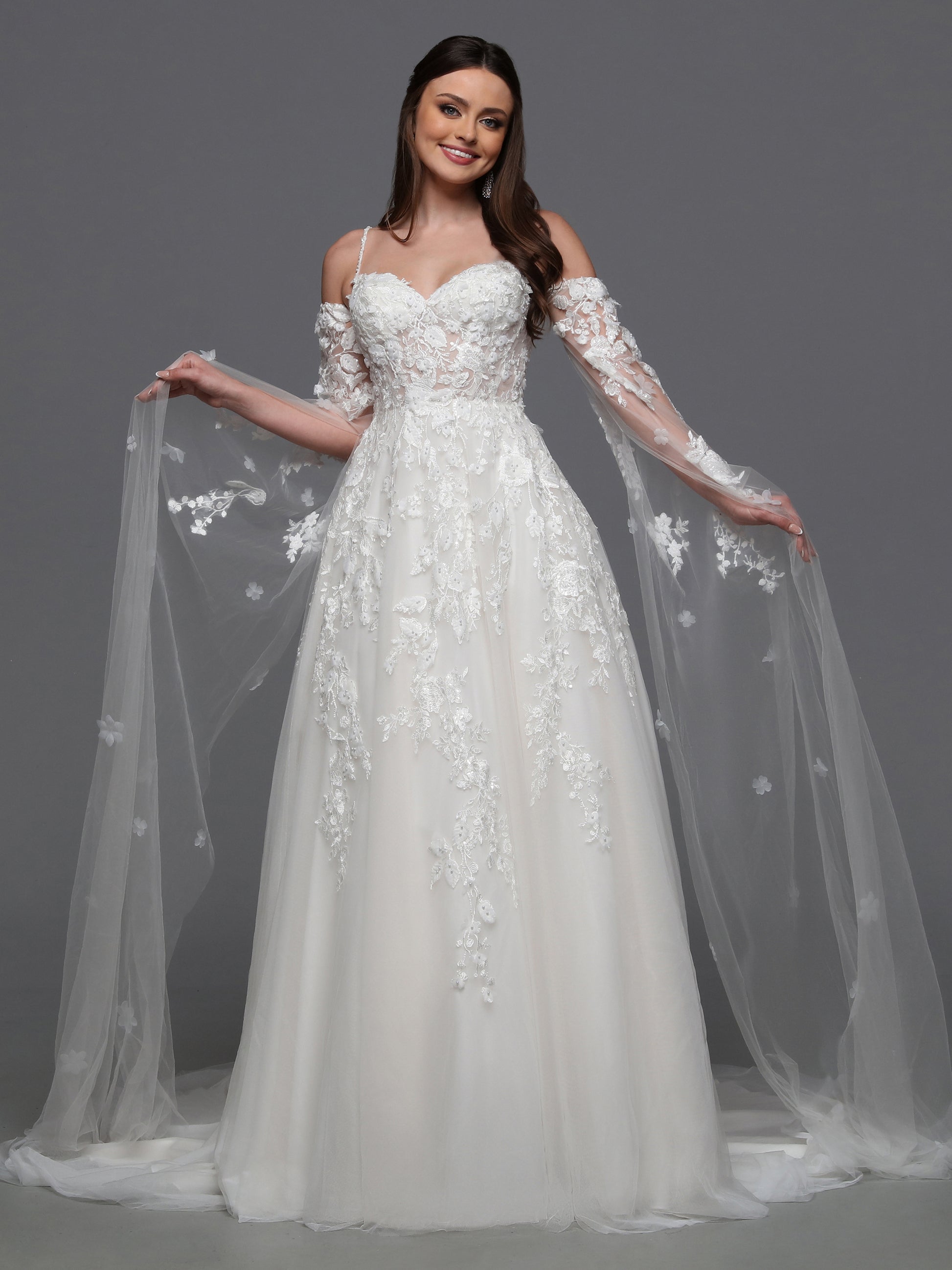 Indulge in luxury and grace with the Davinci Bridal 50834 3D Lace A Line Wedding Dress. Adorned with a detachable cape sleeves and sheer beading, this gown exudes elegance and sophistication. The 3D lace detail adds a touch of artistry, making you feel like a walking masterpiece on your special day. One of our most unique detachable styles, this wedding dress has lace gauntlets with veil wings that add drama to your portraits and your walk down the aisle.