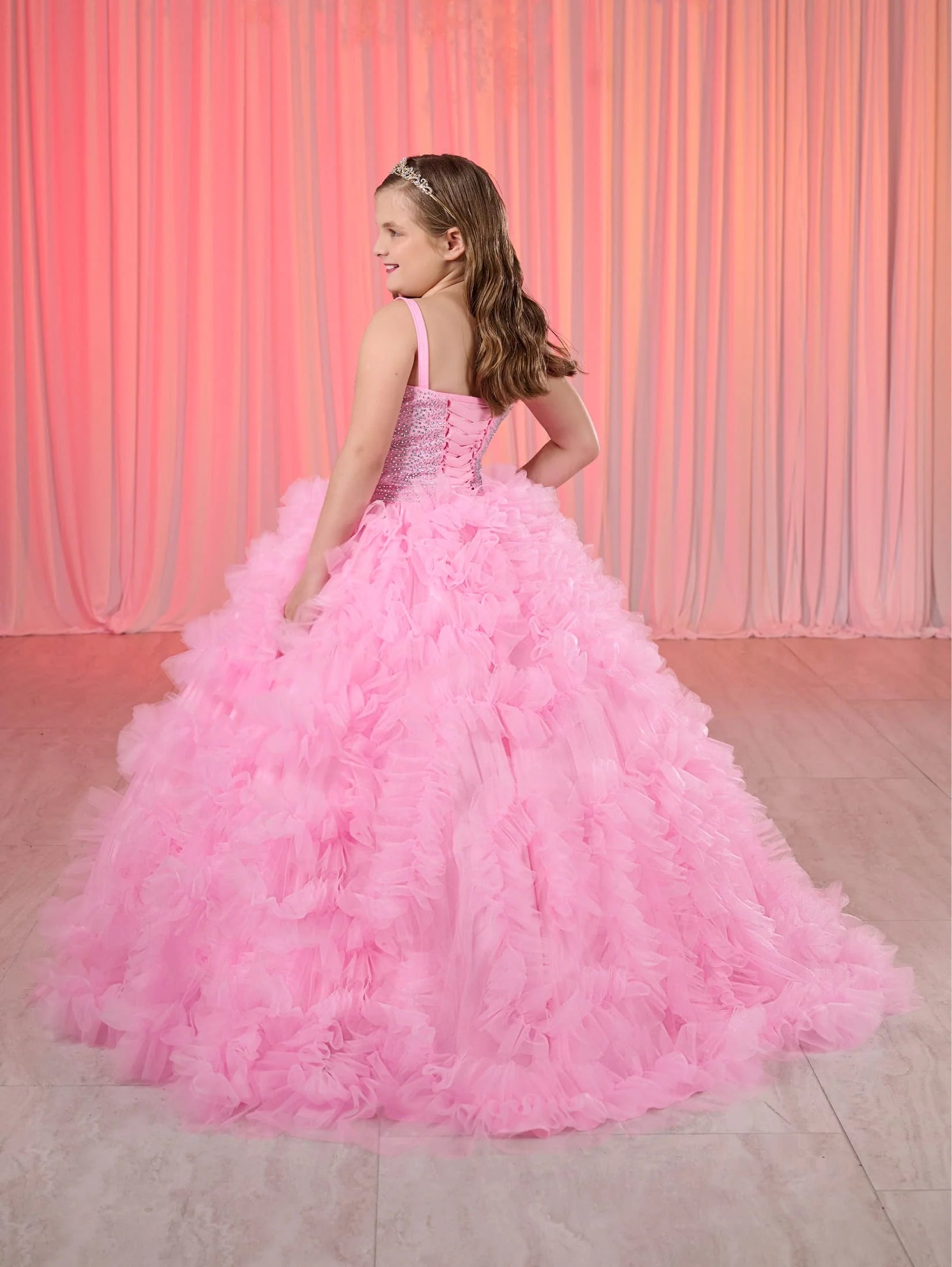 Rule the pageant stage with the Tiffany Princess 80023MQ Girls Ruffle Dress. This stunning ball gown features a crystal-embellished corset bodice and flowing ruffled skirt, perfect for making a grand entrance. The elegant design will have your little girl feeling like royalty, while the comfortable fit allows for graceful movement