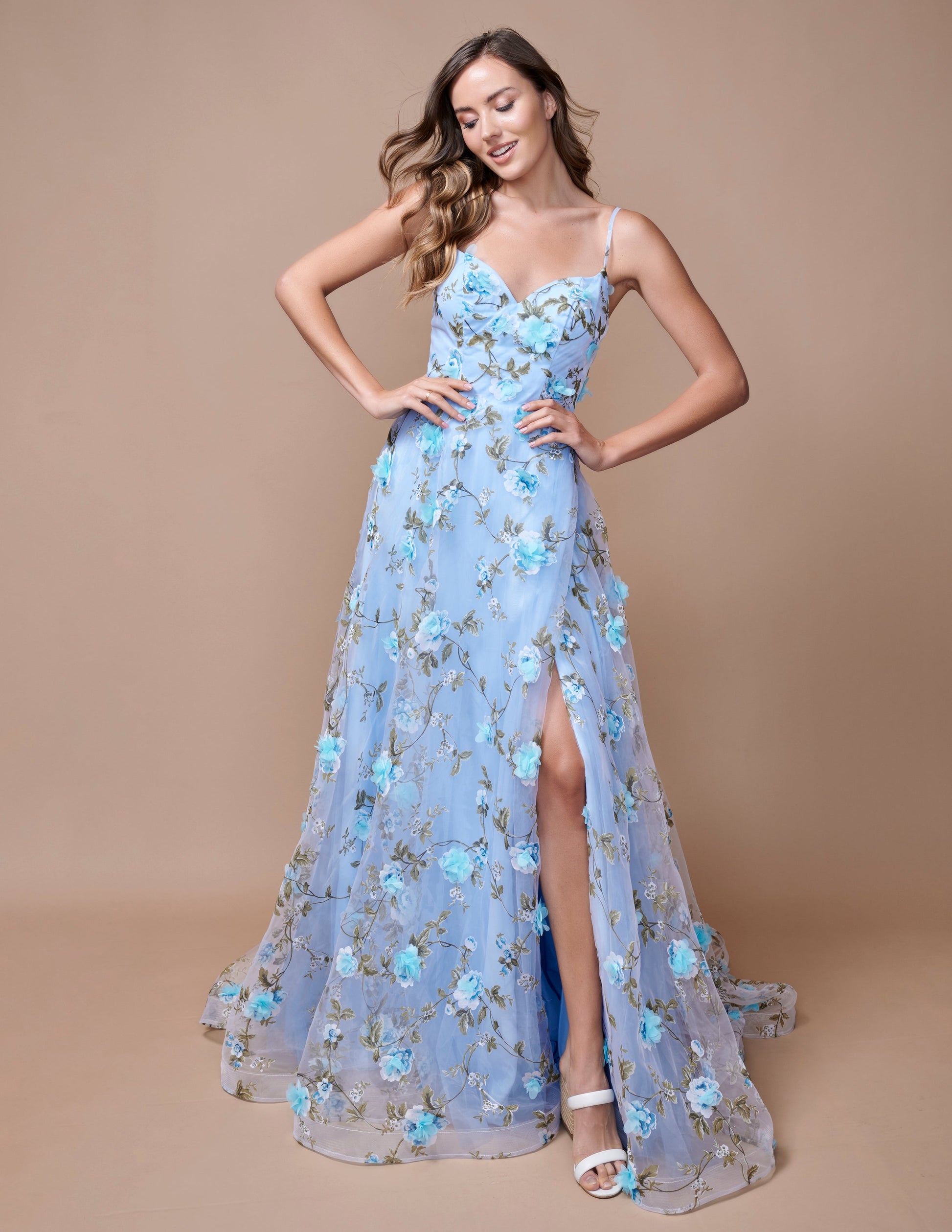 Expertly designed for a sophisticated look, the Nina Canacci 9150 Maxi Dress is the perfect choice for prom or any formal event. This stunning A-line gown features a floral print, 3D detailing, and a V-neckline that will flatter any figure. With a dramatic slit, you'll make a statement as you dance the night away.