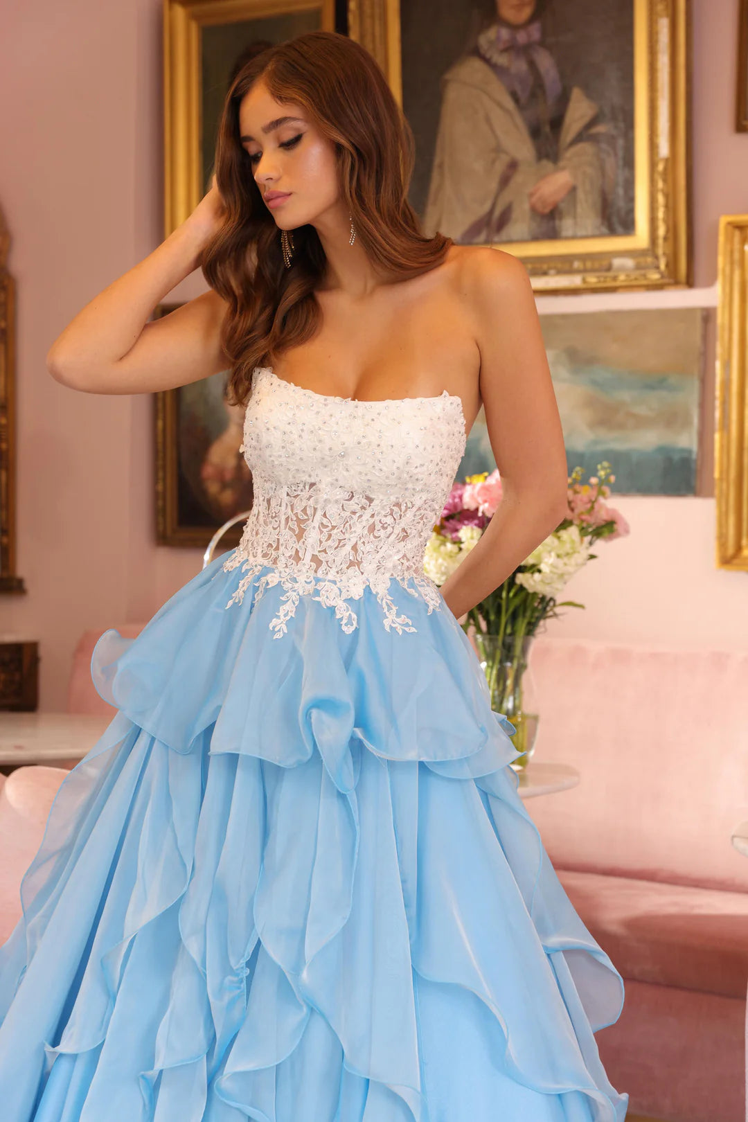 The gown in style 29133 by Ava Presley embodies elegance and fantasy, making it a stunning choice for formal events. The light blue hue gives the dress a fairytale-like quality, while the strapless design adds a touch of modern sophistication.&nbsp;The bodice features intricate lace detailing with beadwork, creating a textured and luxurious appearance. The lace cascades into the layered skirt, which consists of flowing ruffles, adding movement and a whimsical touch to the overall look. This dress is perfect