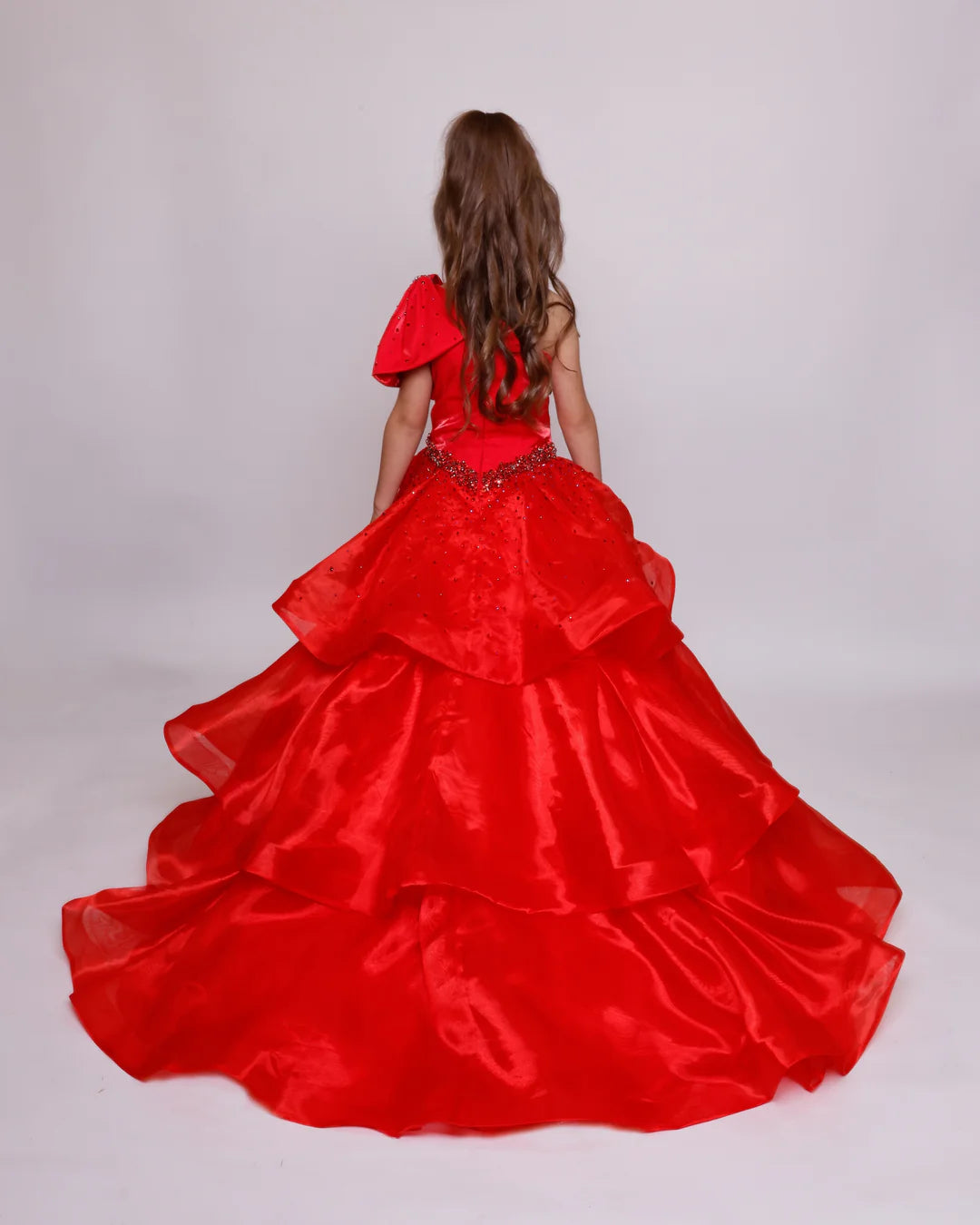 The Ava Presley Girls 39891 Long Pageant Ball Gown is a stunning formal dress designed with a one shoulder style and elegant ruffle details. The drop waist accentuates the silhouette and the layered skirt adds a touch of charm. Perfect for any special occasion, this gown exudes sophistication and grace. Turn heads in this Ava Presley 39891