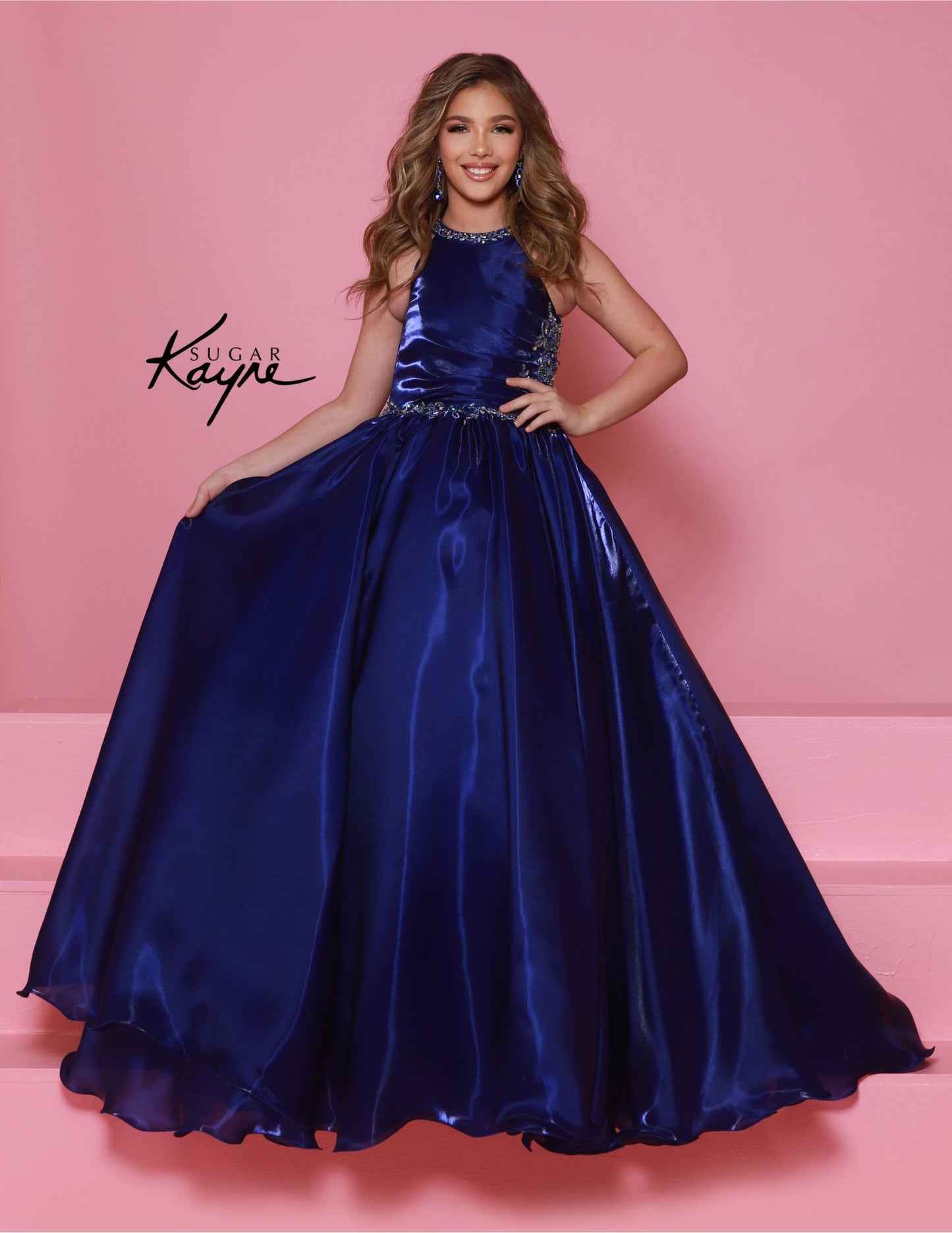 This stunning Sugar Kayne C379 pageant dress features a high neck and A-line design with shimmering beaded details. The elegant ballgown silhouette is perfect for any formal event, ensuring your little girl looks and feels like a princess. Make a statement with this beautiful and eye-catching dress. Step into the spotlight and embody the dazzling diva within! This mirror organza ballgown, with its elegant halter-style neckline, guarantees you’ll captivate the audience with both grace and style.&nbsp;

Sizes