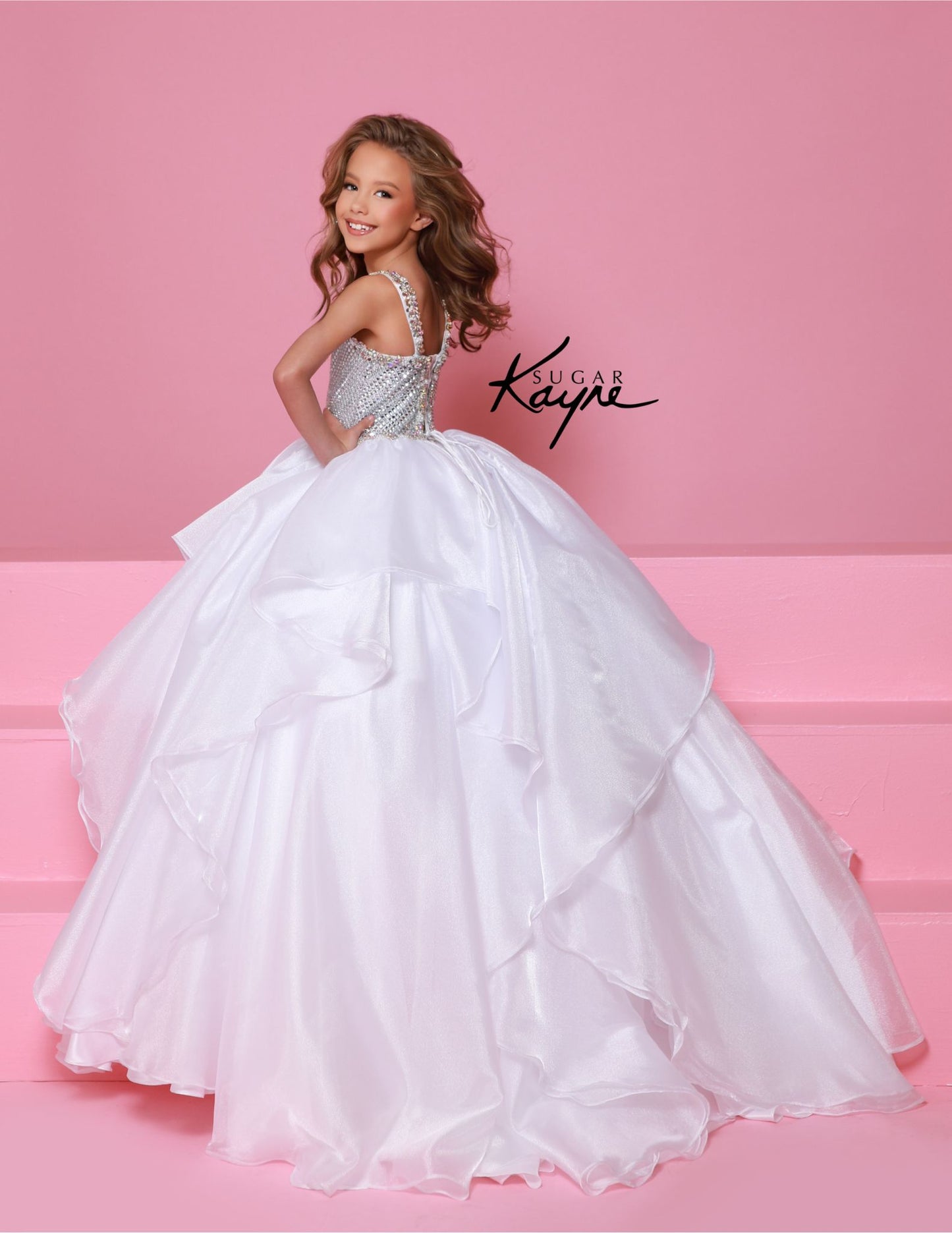 Step onto the pageant stage with confidence in the Sugar Kayne C383 Girls Pageant Dress. This stunning ballgown features a crystal bodice that will shimmer and shine under the lights, while the ruffle detail adds a touch of playful elegance. The layered skirt adds volume and movement, making you the star of the show. Make a dramatic statement at your next pageant with this stunning diamond mesh dress. The ruffled shimmer organza skirt completes the look, offering a perfect blend of elegance and flair.

Size