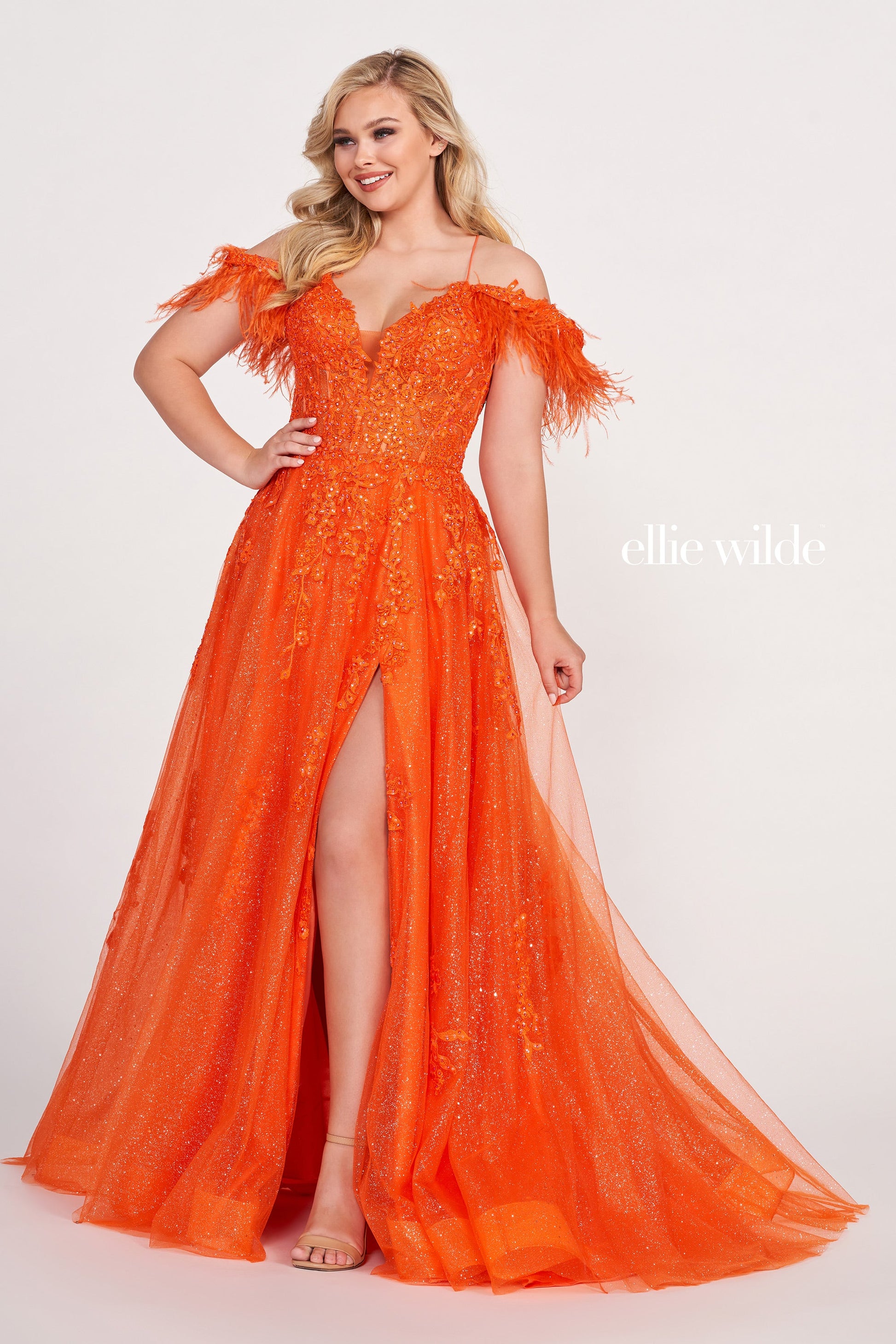 The Ellie Wilde EW34066 is a stunning A-line gown with a sheer sequin corset and feather off-the-shoulder detail. Boasting a dazzling shimmer finish and dramatic slit, this exquisite dress will make you the belle of the ball.  Sizes: 00-16  Colors: ORANGE, RED, PERIWINKLE, IRIS