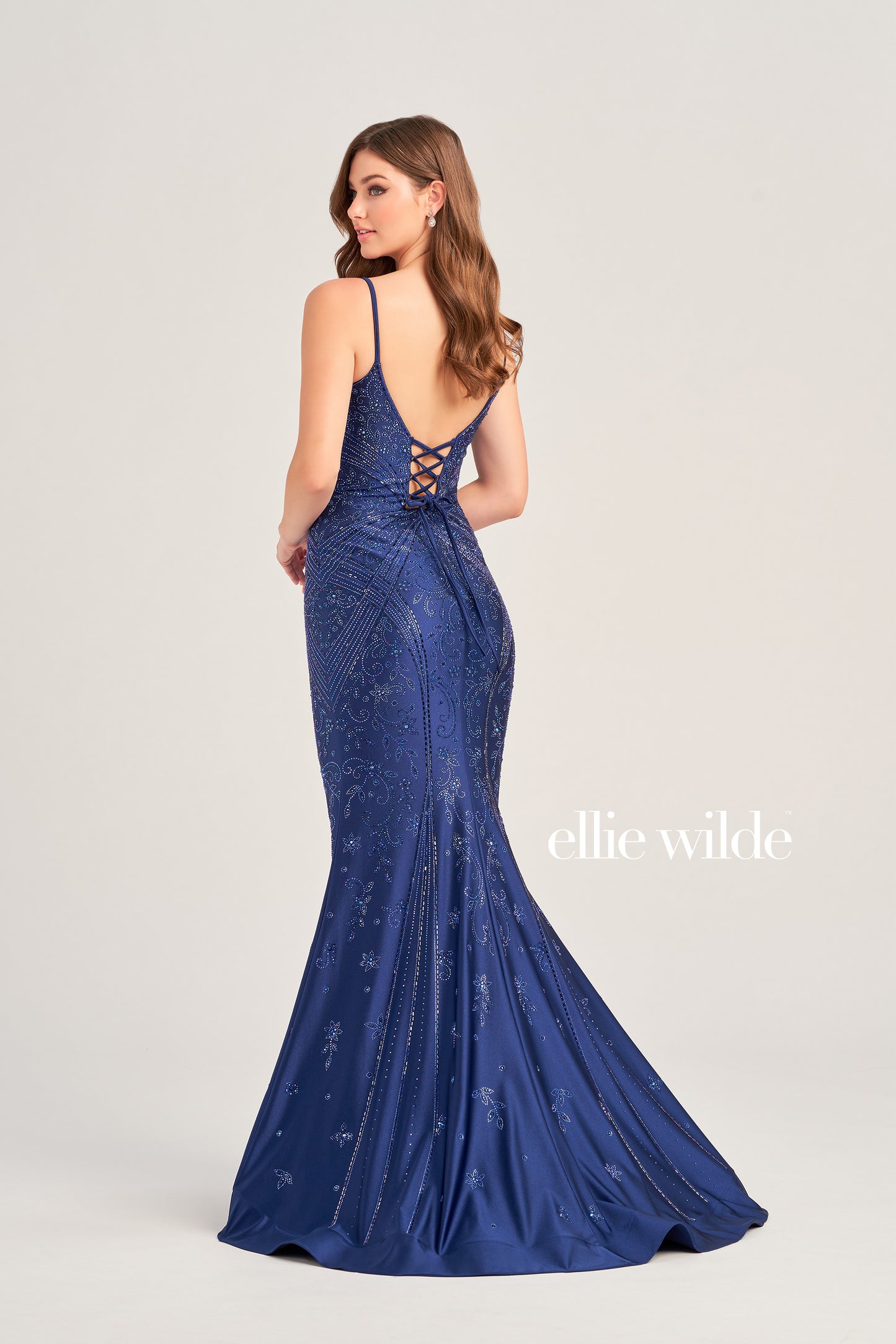 Look stunning in the Ellie Wilde EW35002 prom dress! Crafted from luxurious crystal jersey fabric, this mermaid evening gown features a corset-style bodice and a snug fit for a captivating silhouette. Decorated with shimmering Crystal accents, this dress adds sparkle and shine for an unforgettable formal look.  COLOR: BLACK, NAVY BLUE, ROYAL BLUE, TEAL, HOT PINK, RUBY, ORCHID SIZE: 00 - 24