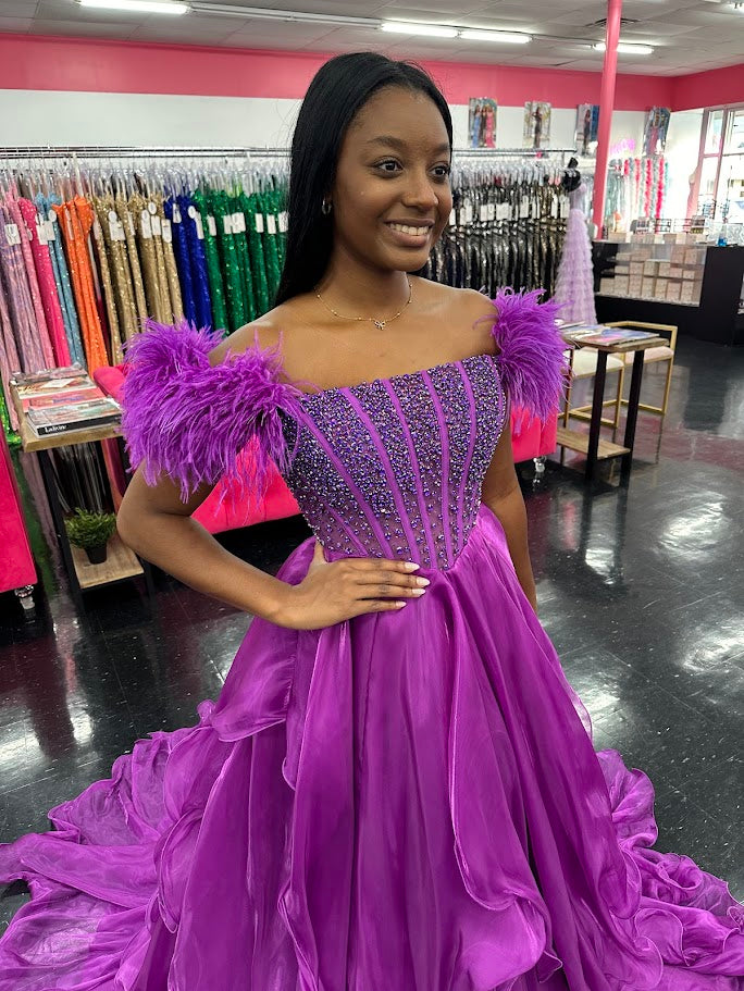 The Ava Presley 39553 Sheer Crystal Corset Pageant Dress is a stunning A Line gown featuring layers of shimmering organza and delicate feather accents. The off-the-shoulder design adds a touch of elegance, while the crystal corset and ruffled detailing add a touch of glamour. Perfect for prom or any special occasion.

Sizes: 8

Colors: Purple