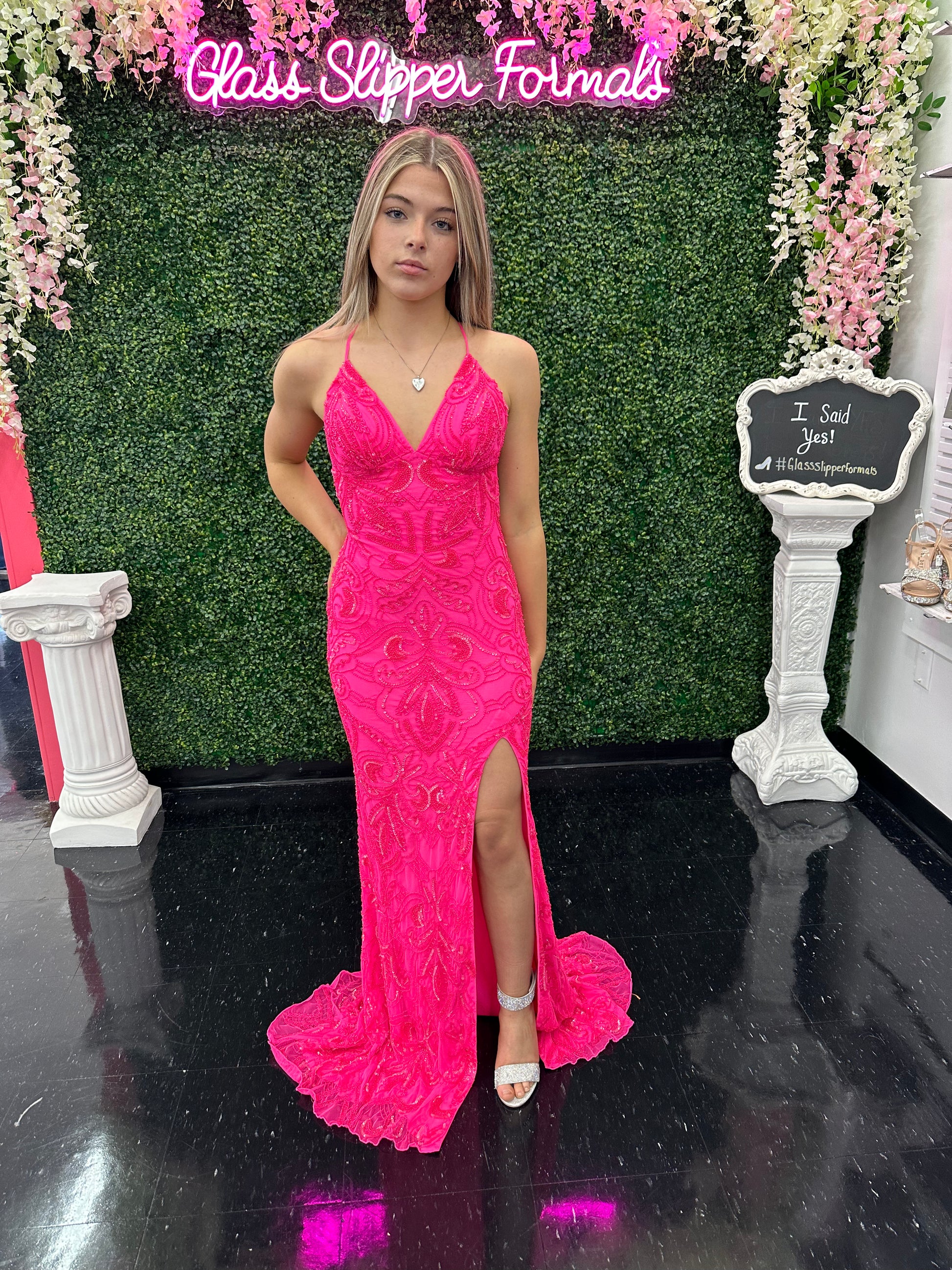 This Amarra 94143 long prom dress boasts a gorgeous neon pink hue, adorned with intricate beading for a touch of sparkle. The backless design and high front slit add a sultry touch to this formal gown, making it perfect for any special occasion. Make a statement and shine all night long.