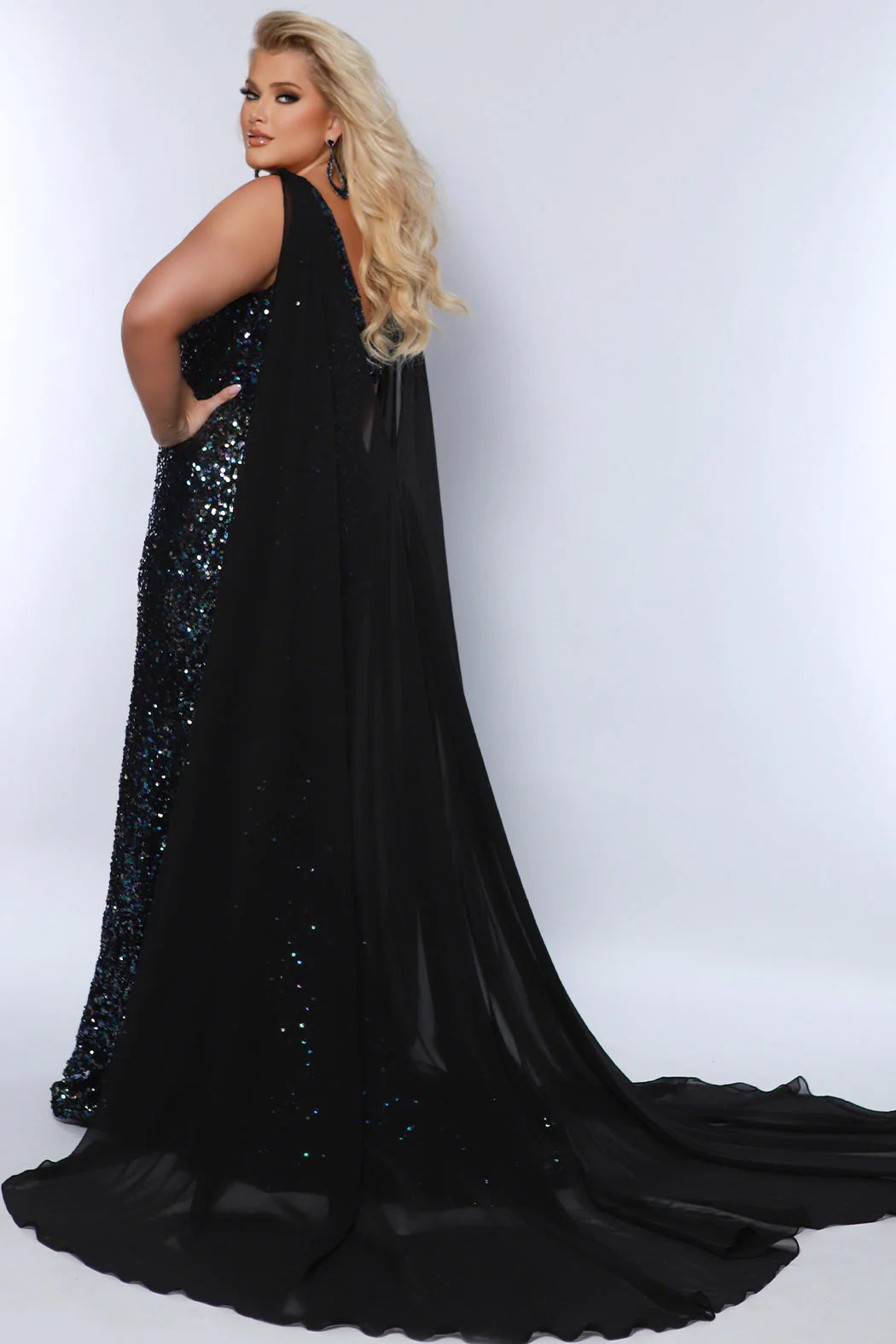 This Sydneys Closet JK2407 Long Fitted Plus Size Sequin Cape Pageant Dress Formal Gown is perfect for formal occasions. Crafted from high-quality materials, this dress features stunning sequin detailing, a long cape-style skirt, and a fitted silhouette, making it a sophisticated choice for any event. With its stylish and timeless design, this gown is sure to make a lasting impression. 