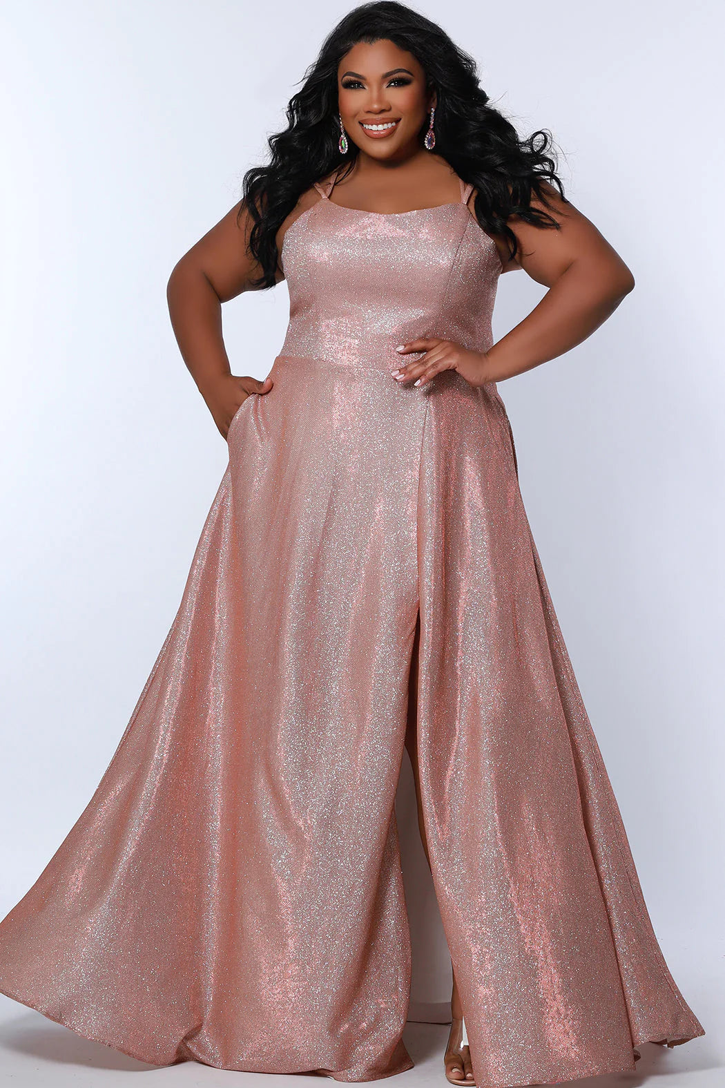 This plus-sized prom dress from Sydney's Closet SC7349 is made of shimmering knit and features an A-line silhouette, scoop neckline, double straps, zip-up back, natural waist, A-line skirt with slit, and hidden pockets. Fully lined for a comfortable and flattering fit. Perfect for special occasions. Keep it sweet and sparkly when you wear our classic A-line plus size prom dress! 