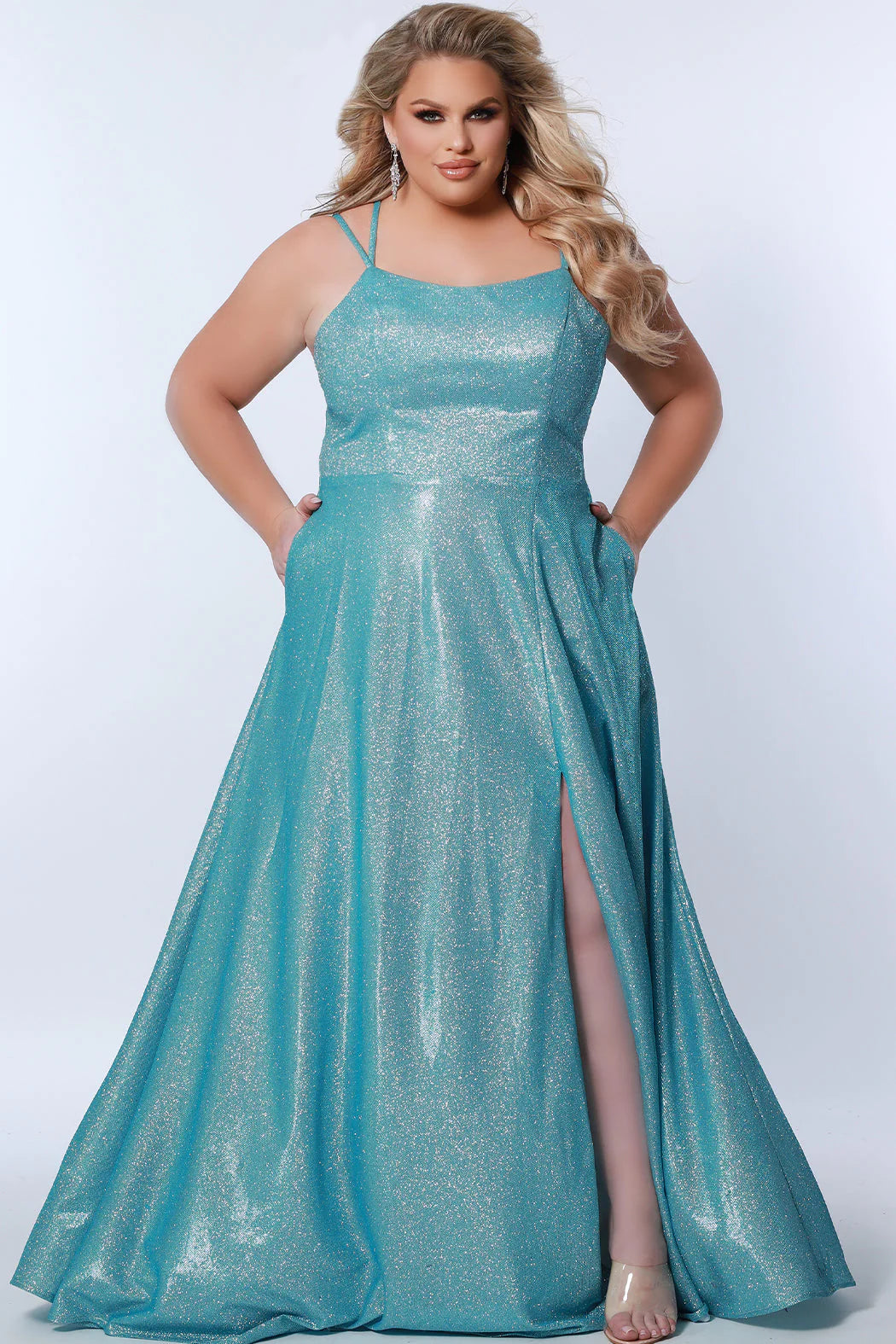 This plus-sized prom dress from Sydney's Closet SC7349 is made of shimmering knit and features an A-line silhouette, scoop neckline, double straps, zip-up back, natural waist, A-line skirt with slit, and hidden pockets. Fully lined for a comfortable and flattering fit. Perfect for special occasions. Keep it sweet and sparkly when you wear our classic A-line plus size prom dress! 