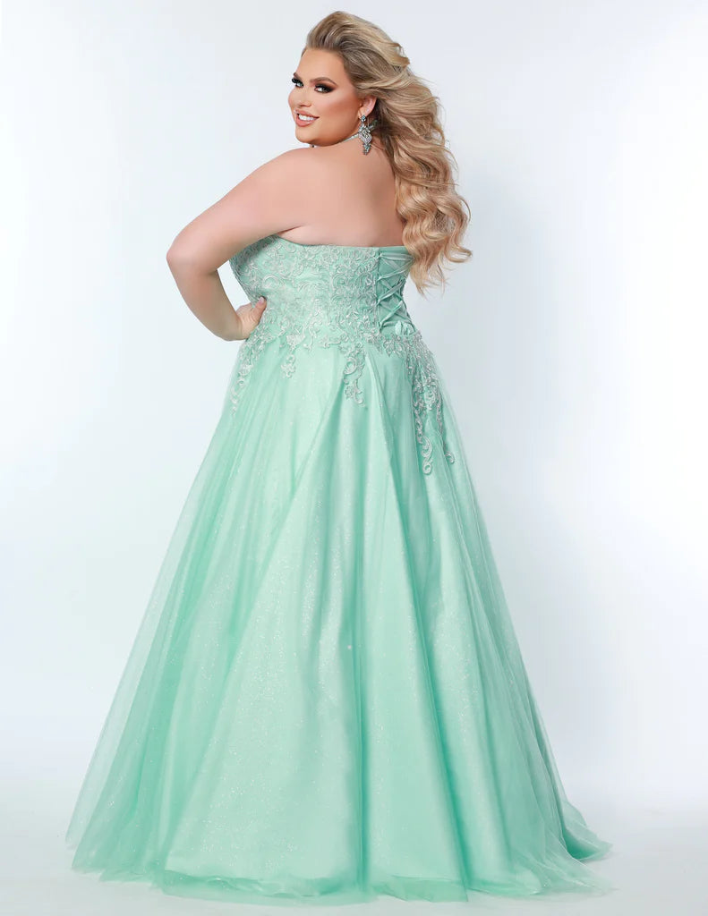 Sydney's Closet SC7352 A-Line Glitter Tulle Lace Appliques Lace Up Back Halter Neckline Plus Size Prom Dress. The Sydney's Closet SC7352 A-Line Glitter Tulle Lace Appliques Plus Size Prom Dress makes a glamorous addition to your wardrobe. This chic dress features an A-line silhouette, glitter tulle overlay, and delicate lace appliques - all crafted with an adjustable lace-up back and halter neckline. An elegant choice for formal occasions.