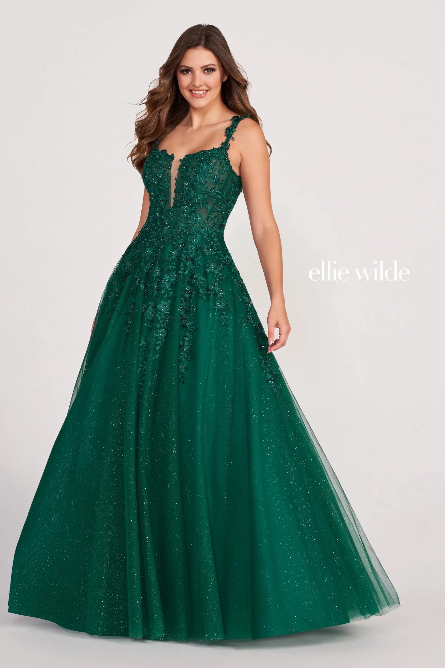 Introducing the Ellie Wilde EW120014 Long Sheer Lace Shimmer Ballgown. This sophisticated formal gown features a sheer bodice with tulle and lace appliqué, an A-line silhouette, plunging V-neckline and natural waist for a flattering fit. The skirt flows to the floor for an airy and graceful look. Make a lasting impression at your prom or special occasion.  Sizes: 00-24  Colors: PERIWINKLE, LAVENDER, RED, ROSE QUARTZ, ROYAL BLUE, WINE, TEAL, WHITE, EMERALD, NAVY BLUE, BLACK, PEONY