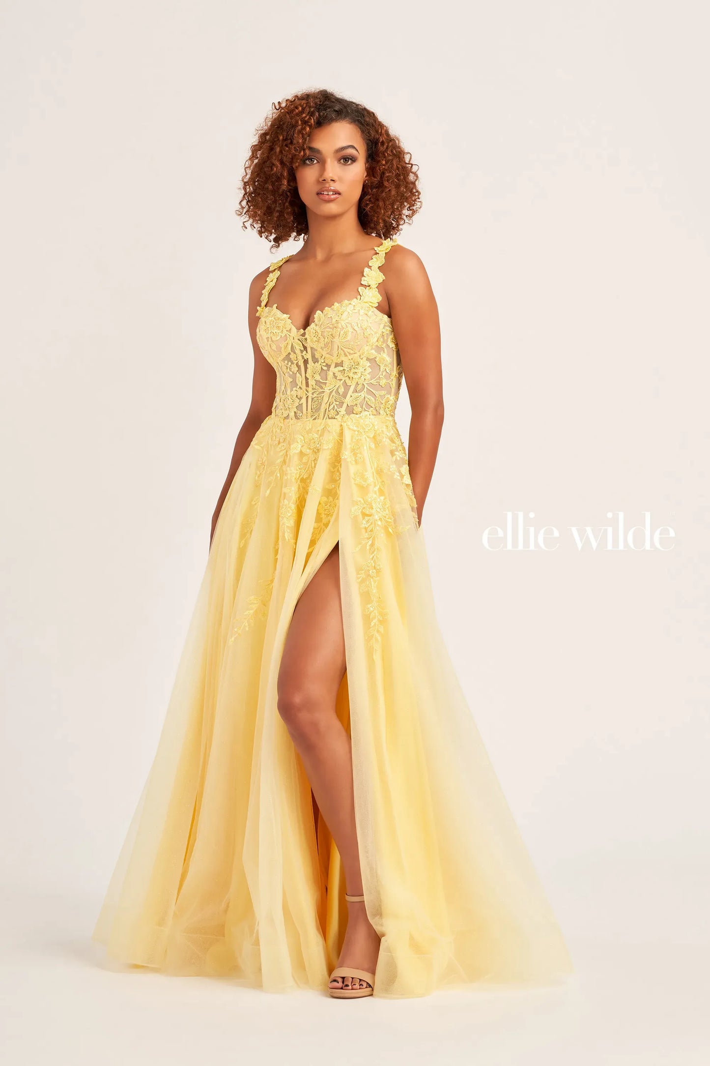 Be the belle of the ball in this Ellie Wilde  EW35101 Sheer Lace Corset Prom Dress. Featuring glitter tulle, sequin tulle, and lace appliqués, this A-line gown boasts a sweetheart neckline and off-the-shoulder sleeves. The front slit and 3D flower lace strap add extra flair to this elegant and glamorous look.  Sizes: 00-24  Colors: RED, LIGHT YELLOW, EMERALD, ROYAL BLUE, BLUEBELL