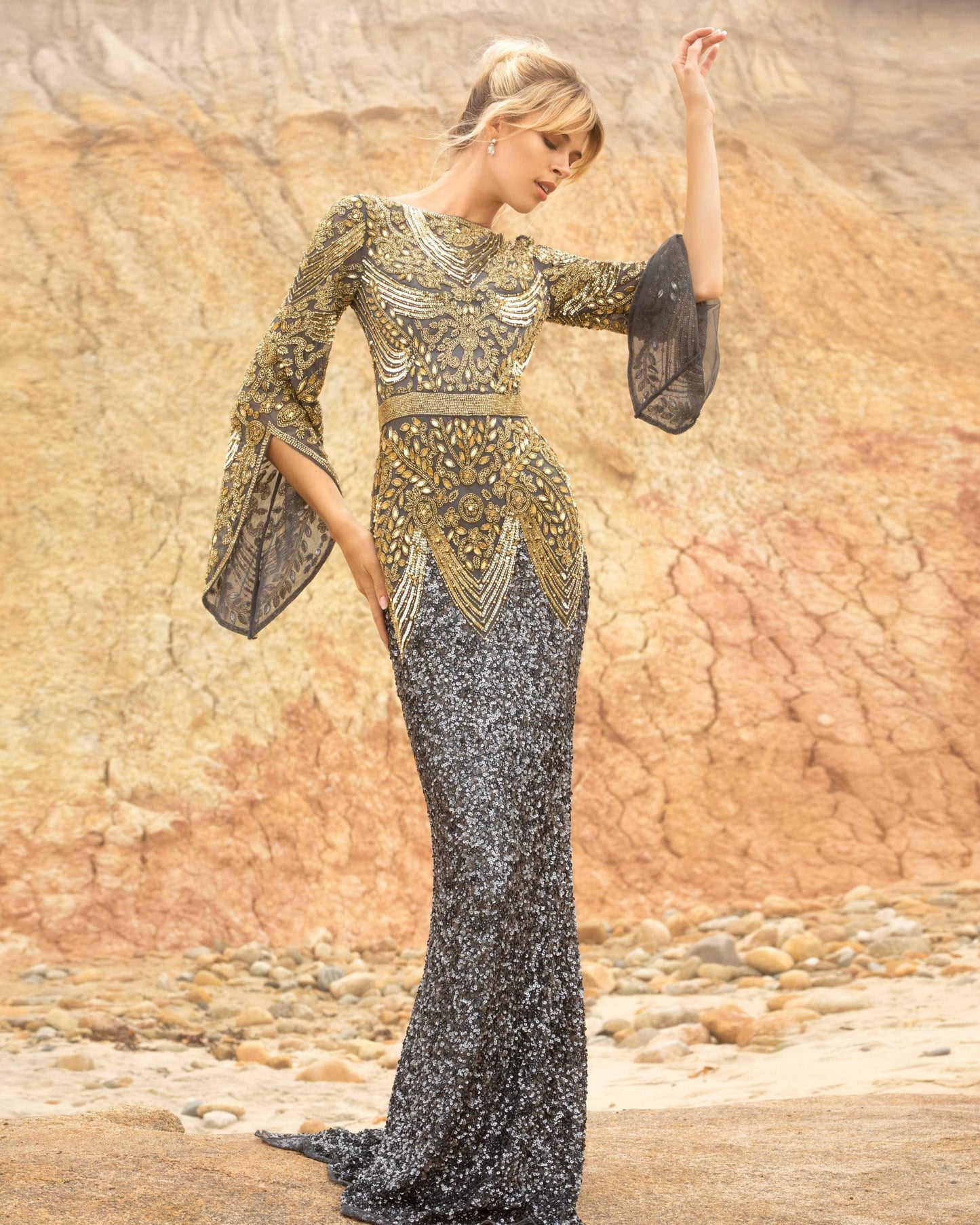 Primavera Couture 3680 This is a long hand beaded evening gown with a bateau neckline and sheer long embellished bell sleeves. It is multi colored and fitted to the floor with an embellished waistline. Available colors:  Black Nude, Charcoal Gold, Forest Green  Available sizes:  0-24