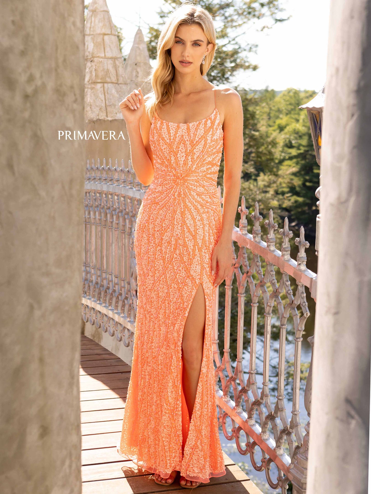 Primavera Couture 3959 This is a coral fully sequined prom dress.  It features a starburst in the front of the dress with waterfall streaming sequins up and down the long length of the dress.  It has a corset open back and a side slit,  Available Size: 2, 10   Available Colors: Coral