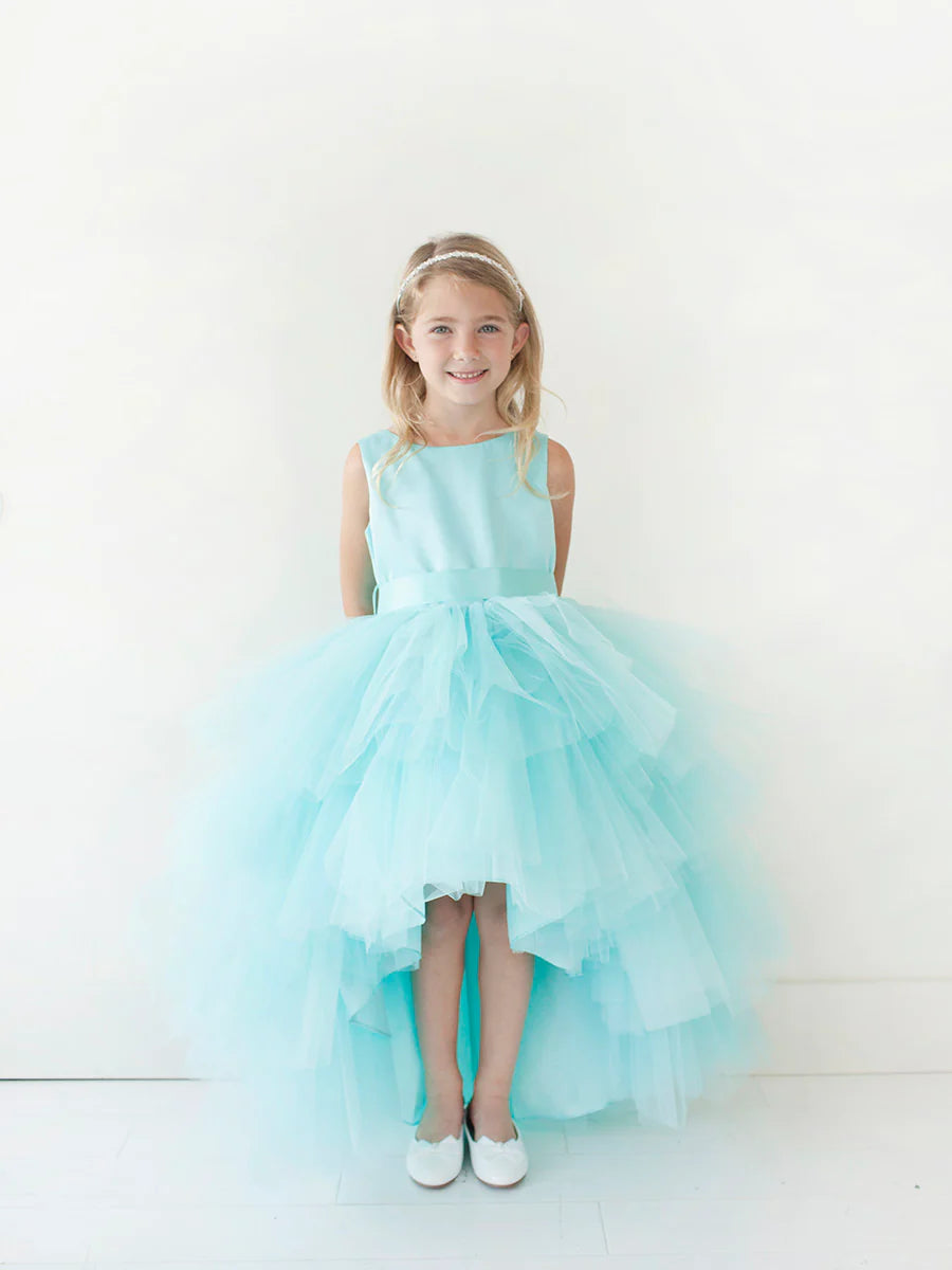 This Tip Top 5658 Girls Layered Tulle High Low Skirt Formal Dress is a perfect choice for that special day. The tulle high-low skirt, satin formal gown, and flower girl satin sash come together to create a beautiful, unique look perfect for flower girls, junior bridesmaids or formal occasions.  Sizes: 6M-16  Colors: Black, Blush, Burgundy, Eggplant, Ivory, Red, Royal Blue, White, Champagne, Lilac, Sky Blue