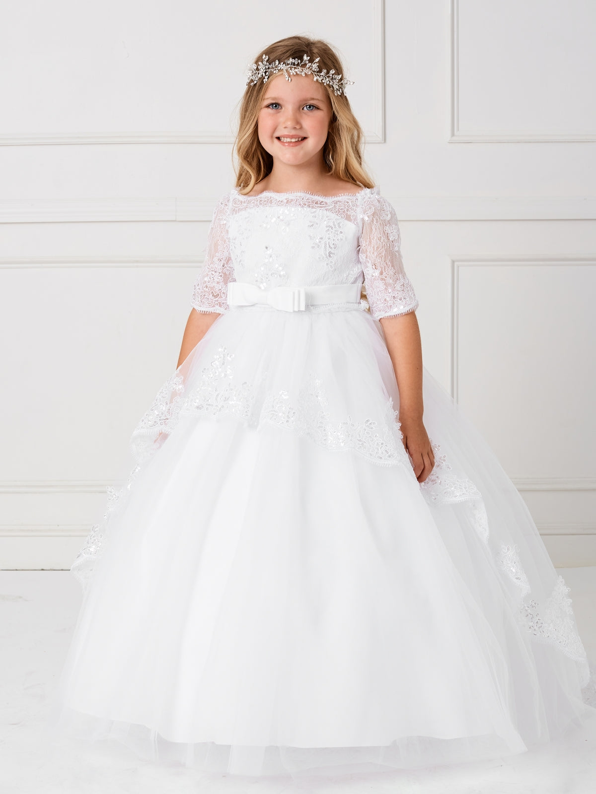 This gorgeous off shoulder dress is perfect for your little girl. The center of the dress has a simple bow at the waist.This dress features a lace peplum skirt with a long train on the back that has beautiful embroidered details. Skirt has additional netting crinoline underneath that can be puffed up if extra fullness is desired. Fully lined, zipper back, and satin sash tie-back.  Available Size: 4  Available Color: Ivory