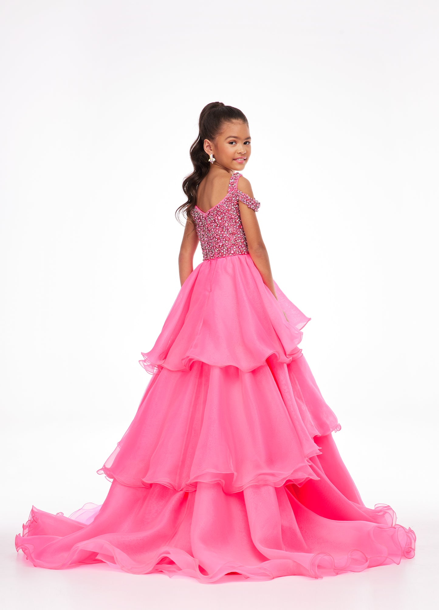 Ashley Lauren Kids 8101 Girls Pageant Dress.  The crystal encrusted bodice on this kids Pageant Gown consists of a slight V-Neckline and off the shoulder straps. The A Line multi-tiered organza ruffle skirt completes the look with a long train.   Available colors:  Hot Pink, Lilac, Turquoise