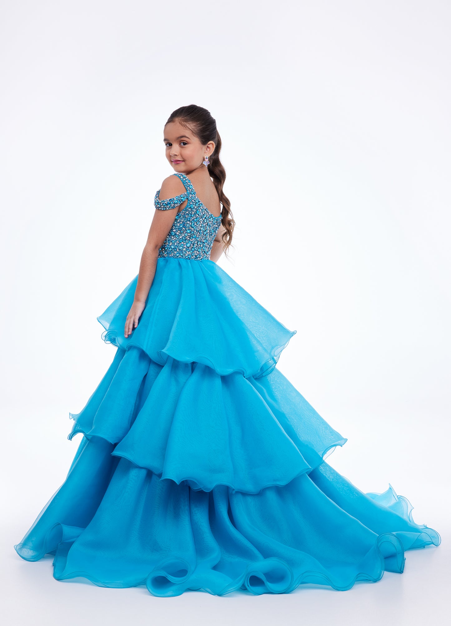 Ashley Lauren Kids 8101 Girls Pageant Dress.  The crystal encrusted bodice on this kids Pageant Gown consists of a slight V-Neckline and off the shoulder straps. The A Line multi-tiered organza ruffle skirt completes the look with a long train.   Available colors:  Hot Pink, Lilac, Turquoise