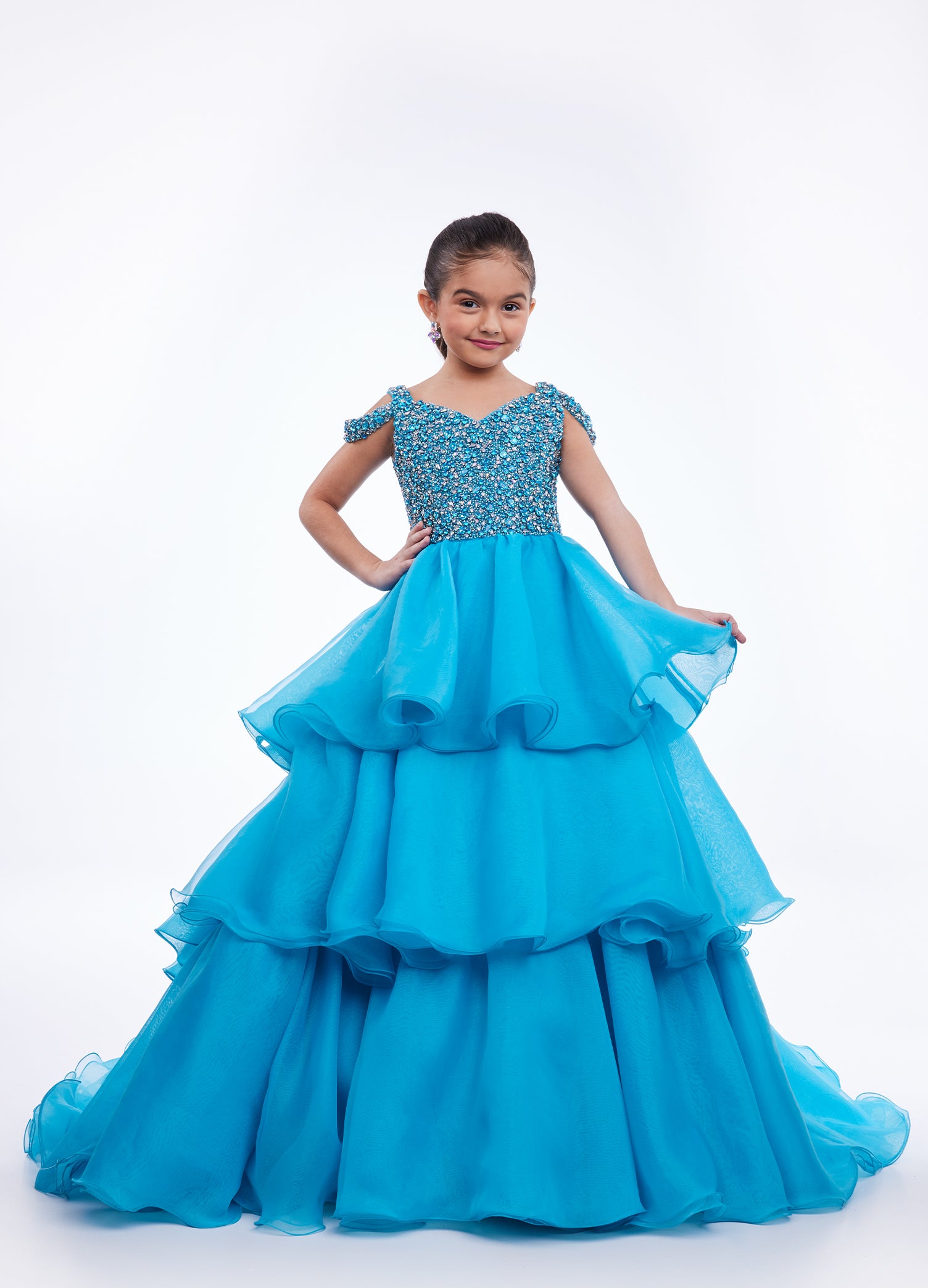 Ashley Lauren Kids 8101 Girls Pageant Dress.  The crystal encrusted bodice on this kids Pageant Gown consists of a slight V-Neckline and off the shoulder straps. The A Line multi-tiered organza ruffle skirt completes the look with a long train.   Available colors:  Hot Pink, Lilac, Turquoise