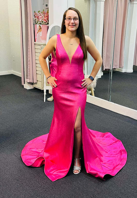 Jovani 06125 is a gorgeous Long Fitted metallic shimmer Formal Evening Gown. Plunging Deep V Neckline with an open V Back. Fit & Flare silhouette with s slit in the thigh and a lush trumpet skirt with Gorgeous sweeping train. Sheer side panels with mesh insert.  Hot Pink  Size 6