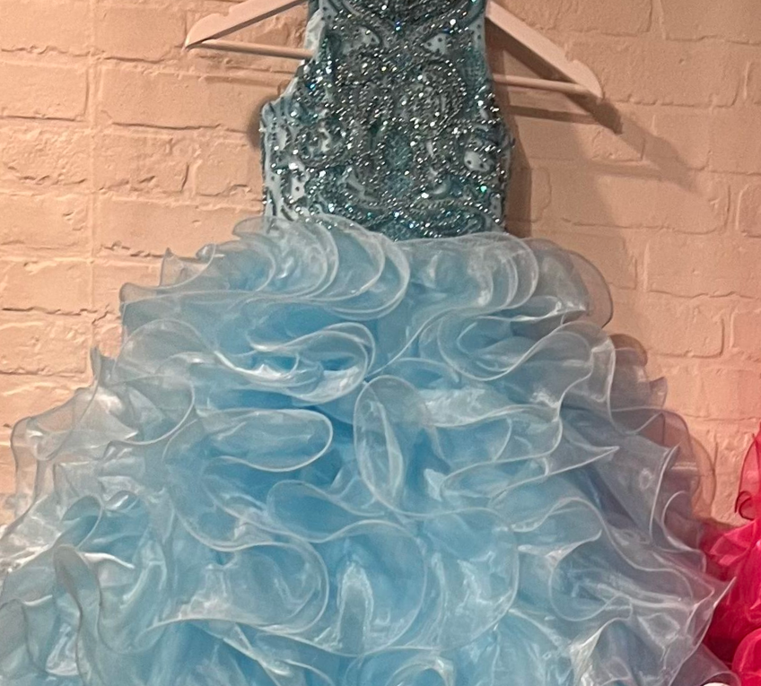 The elegant and sophisticated Sugar Kayne C328 Girls Preteens Pageant Dress boasts a dazzling halter neckline and full ruffle ball gown skirt with a crystal bodice, perfect for making a memorable fashion statement.  Colors: Barbie Pink, Cinderella Blue, Yellow